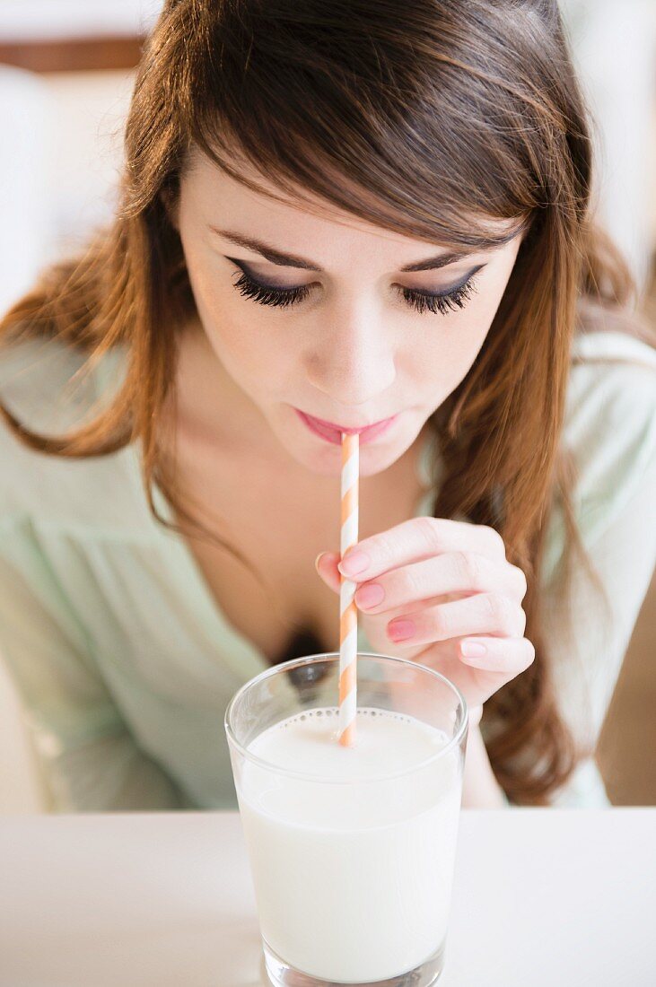Young woman drinking milk through a straw