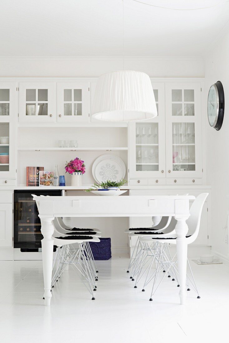 White dining table and classic Eames chairs in front of white dresser in rustic dining room