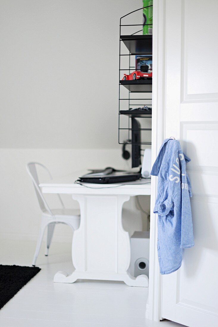 Black and white study area with white designer chair, desk and retro, wall-mounted shelves