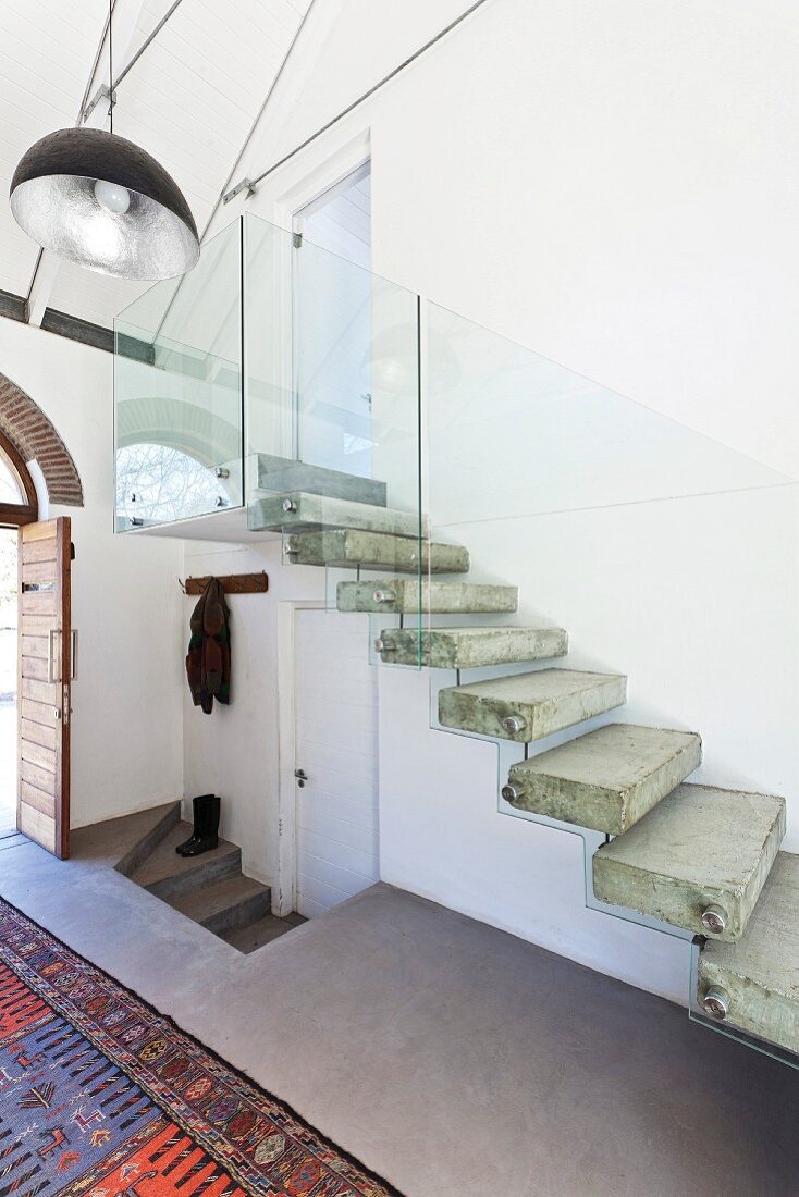 Concrete staircase with floating steps and glass balustrade in foyer