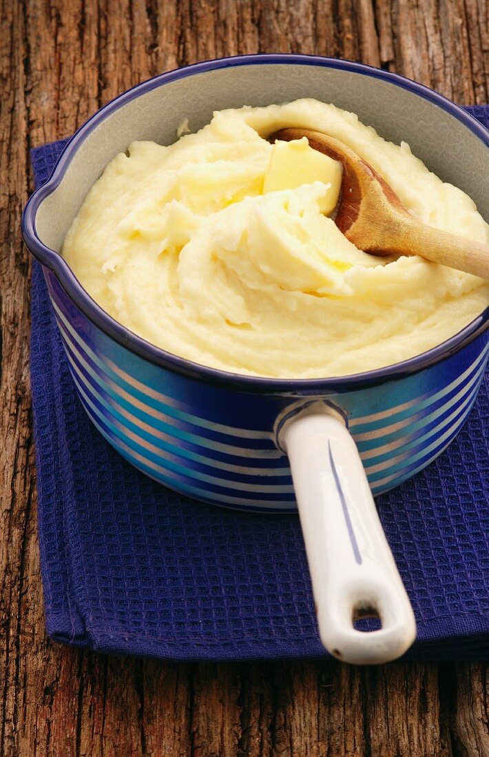 Mashed potatoes with a knob of butter in an enamel saucepan
