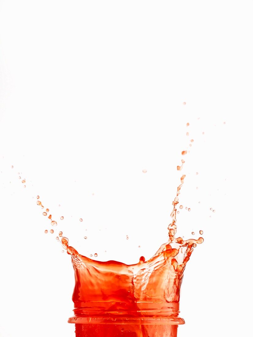 Roter Saft spritzt aus einem Glas