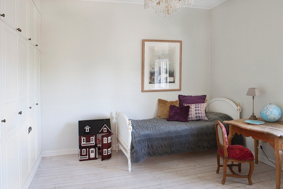 Desk next to single bed with antique, white frame in simple bedroom with fitted wardrobes