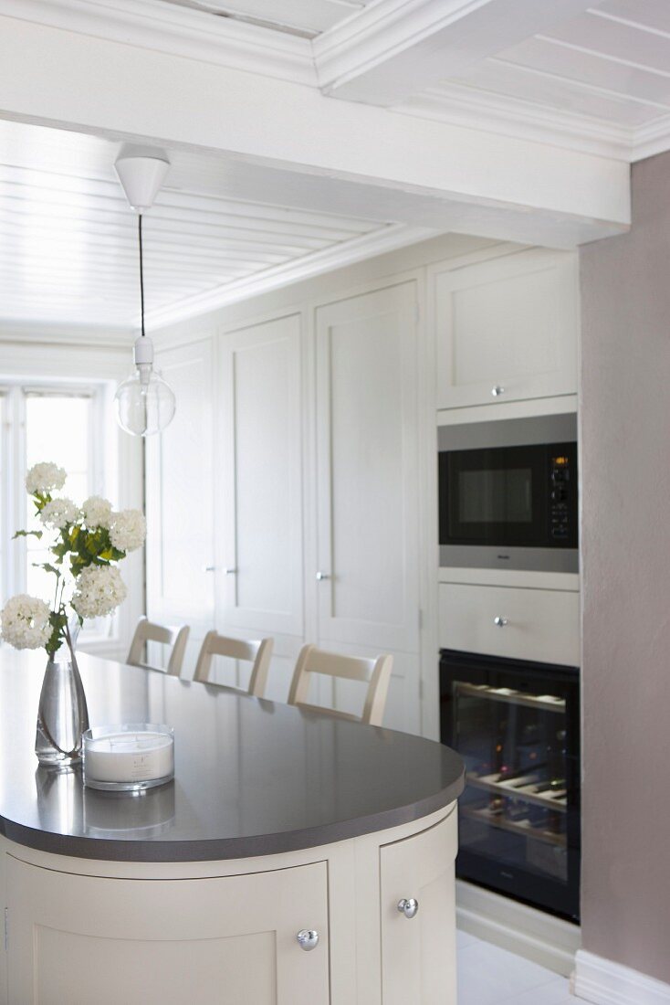 Counter with rounded end and bar stools in pale kitchen