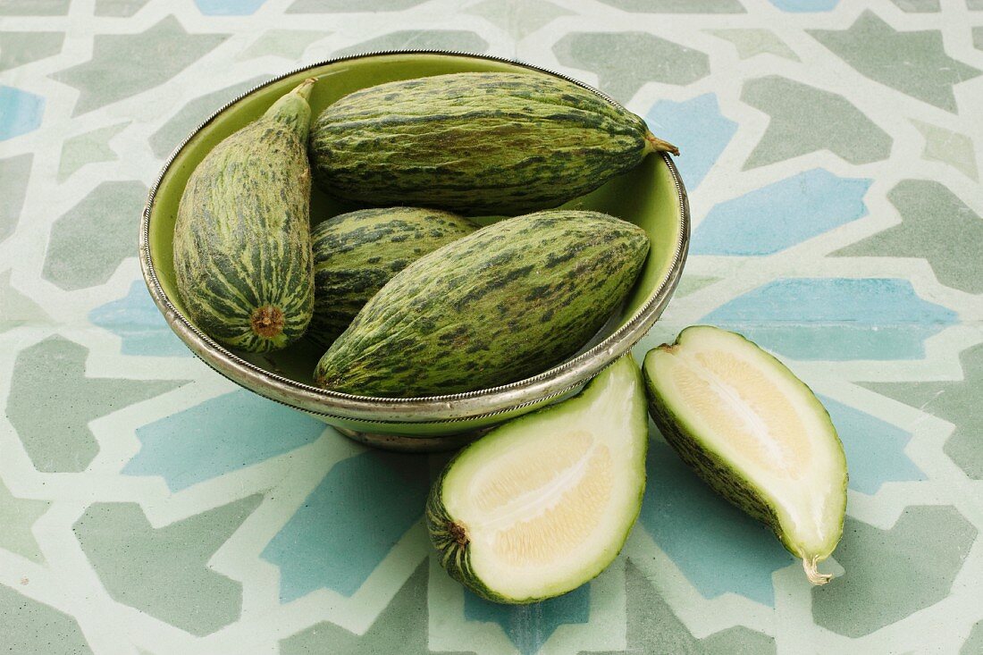 Cucumber melons, whole and halved, in a bowl and next to it