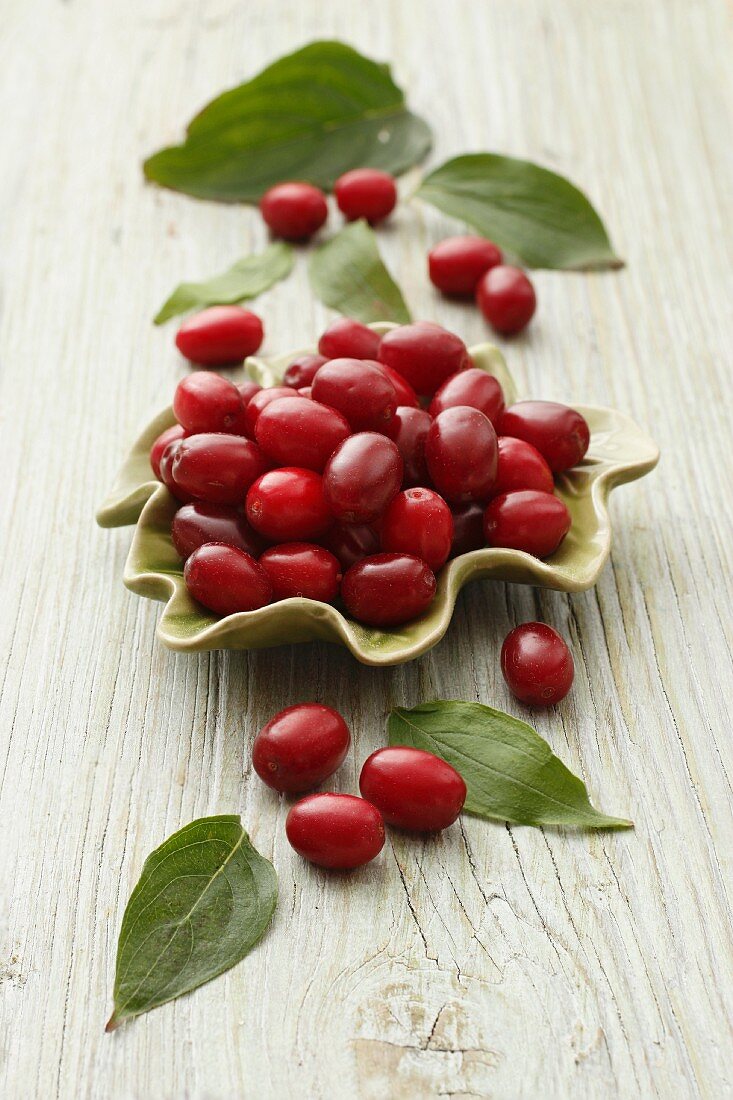 Cornelian cherries with leaves in a bowl and next to it