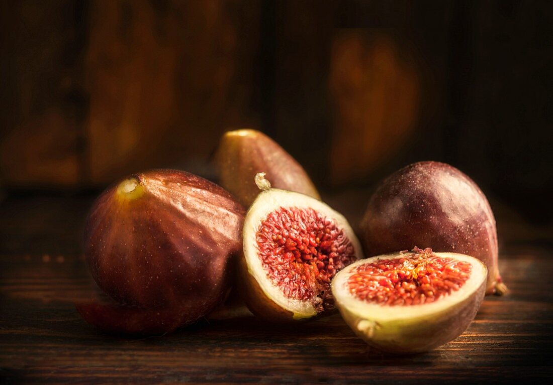 Fresh red figs, whole and halved, on a wooden table