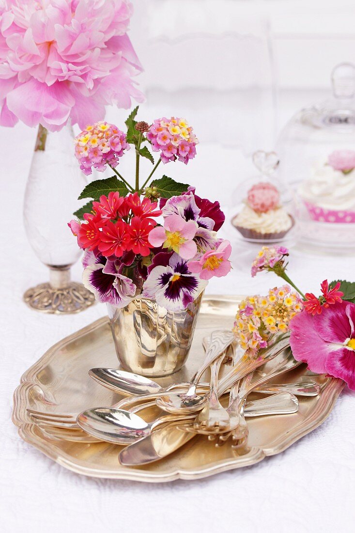 Silver cutlery & flower arrangement in shades of pink on silver tray