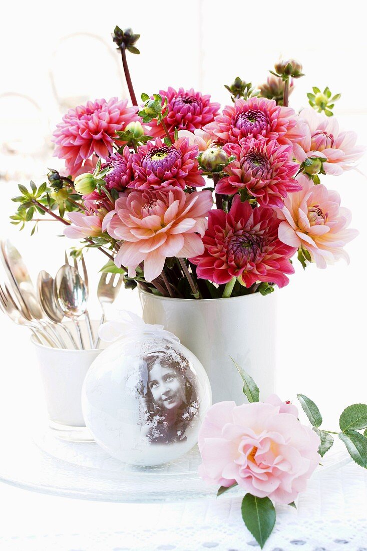 Nostalgic arrangement with vase of dahlias & snow globe on table