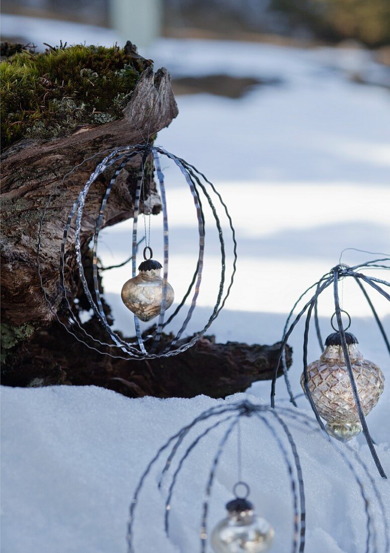 Baubles made from metal rings with silver Christmas baubles hanging from tree trunk in snowy landscape