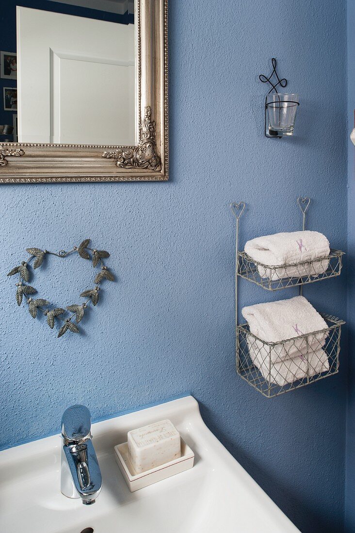 Hängeregal mit weissen Handtüchern an blau getönter Wand im Bad