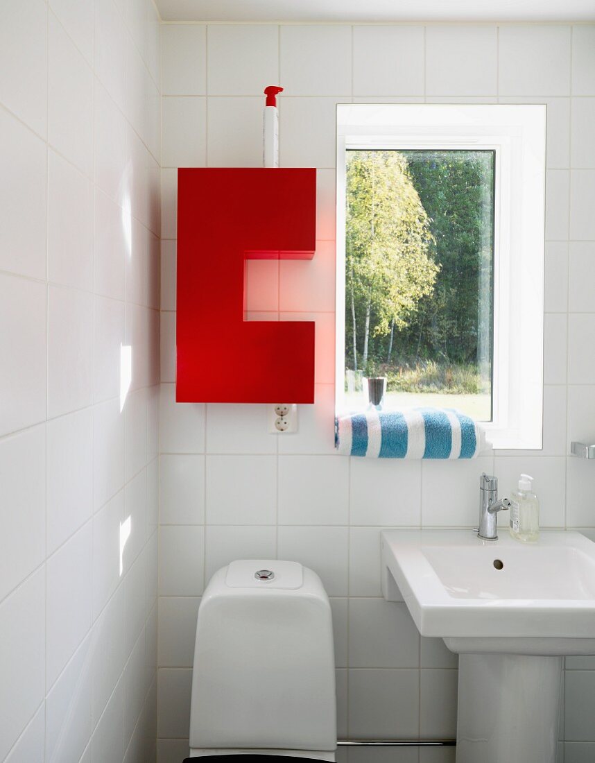Roter Wandschrank neben dem Fenster im weissen Bad