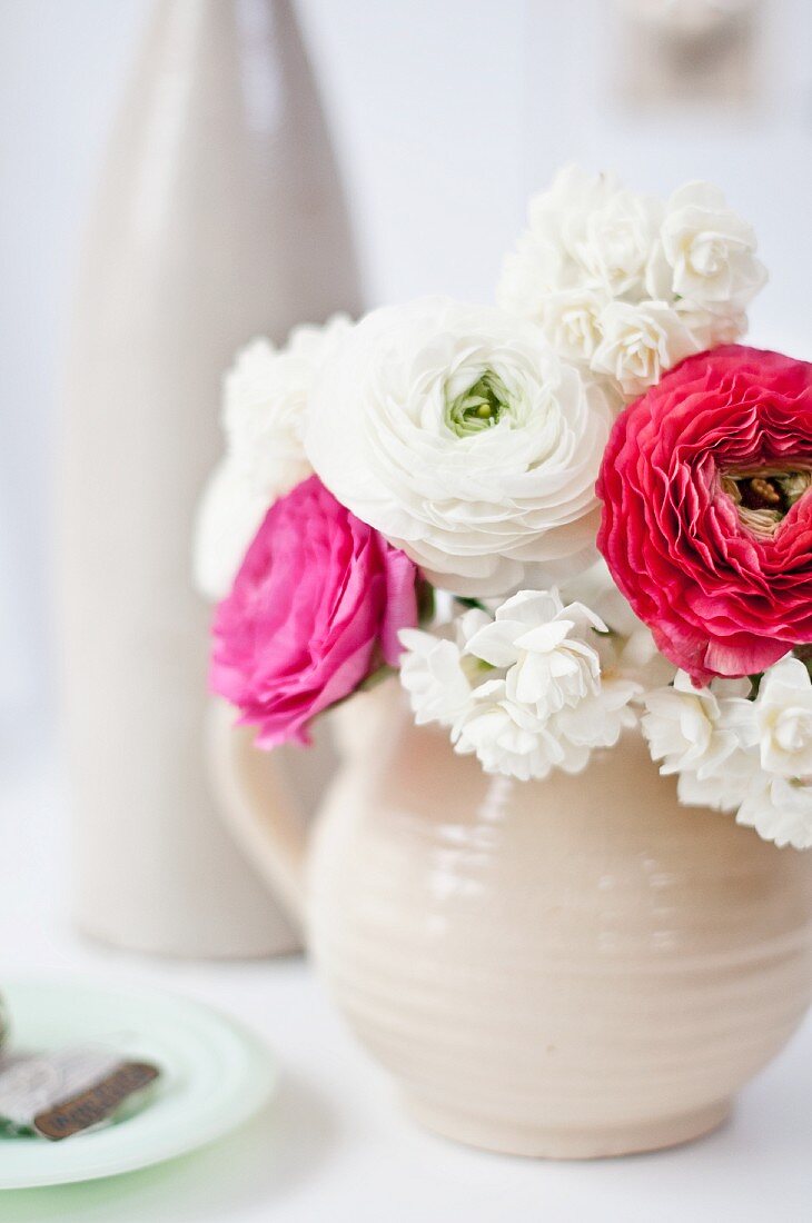 Cream narcissus and ranunculus in pale stoneware jug