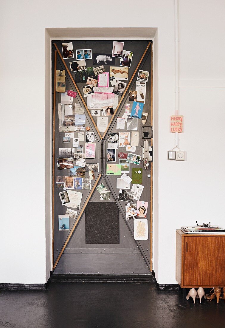 Old steel door used as magnetic pinboard for photos