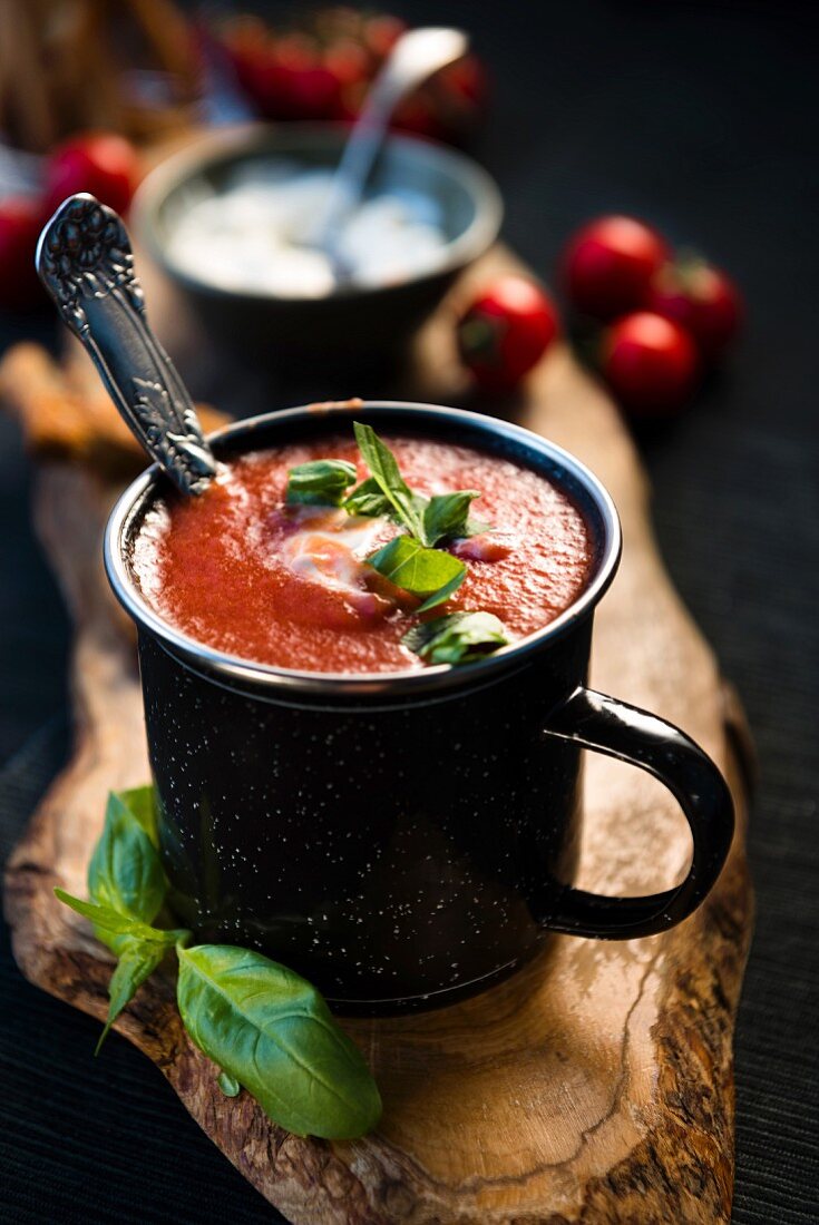 Tomato soup with grissini and fresh basil in an enamel mug