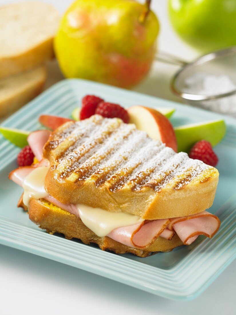 A Monte Cristo sandwich with ham, cheese, icing sugar and fresh fruit