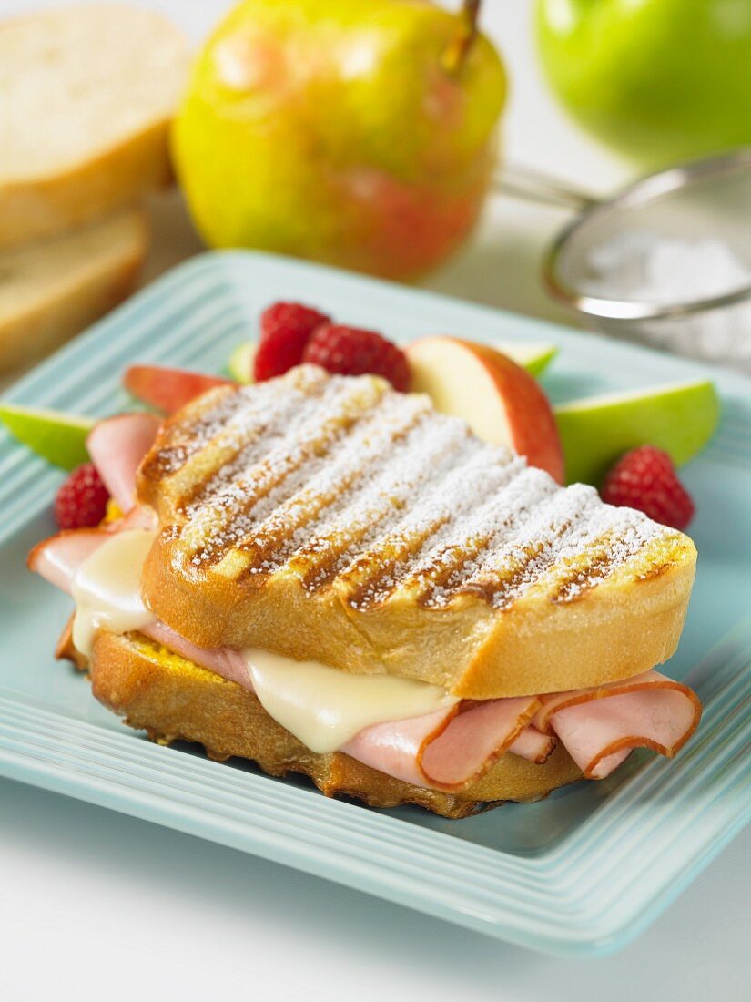 Monte Cristo Sandwich mit Schinken, Käse, Puderzucker und frischem Obst