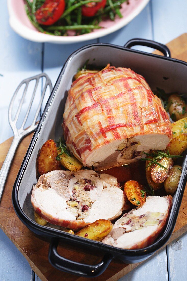 Stuffed turkey breast wrapped in bacon with roast potatoes