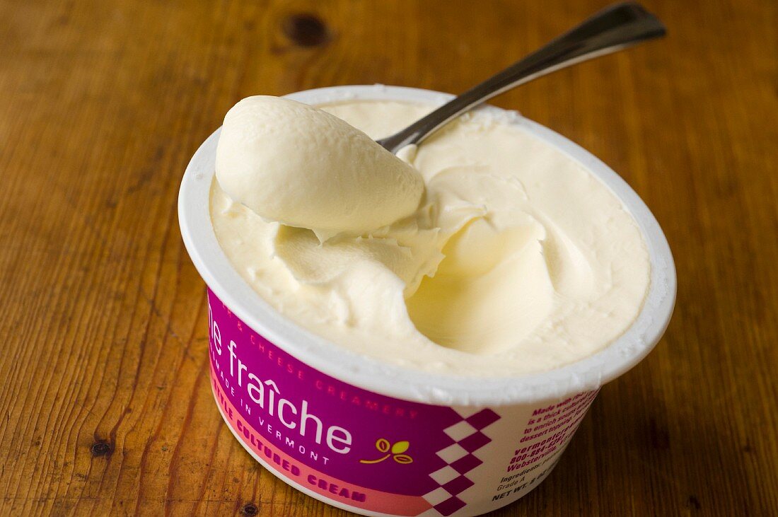 A pot of crème fraîche with a spoon