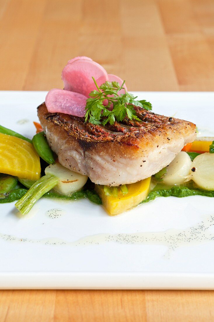 Fried snapper on a bed of spring vegetables with water cress and pickled radishes