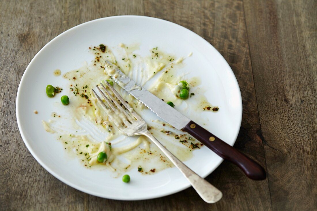 An empty plate with leftover peas