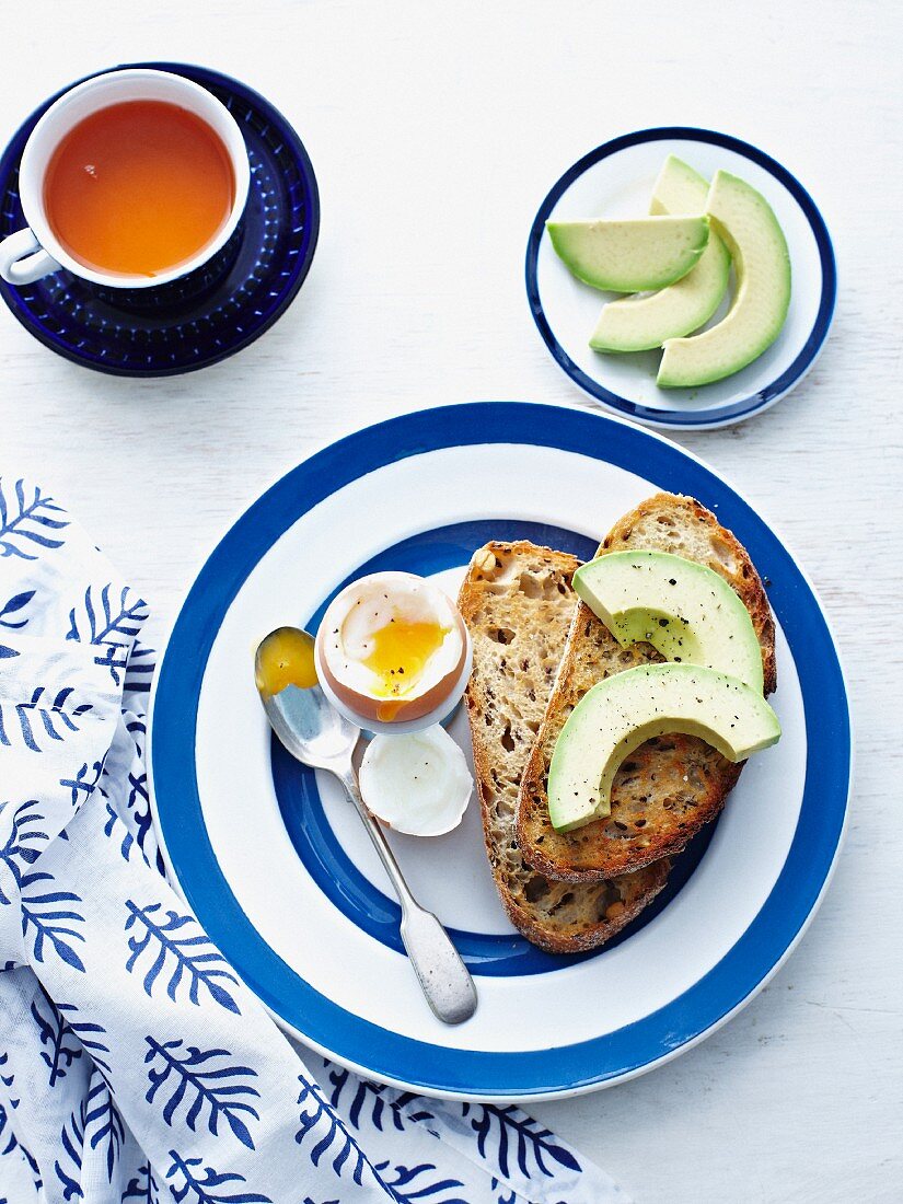 A soft-boiled egg with toast and avocado