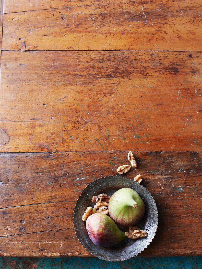 Fresh figs and walnuts in a bowl on a wooden surface