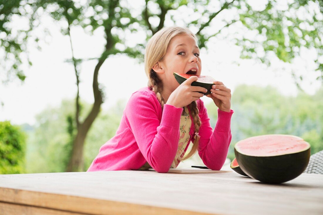 A girl outside eating a watermelon wedge