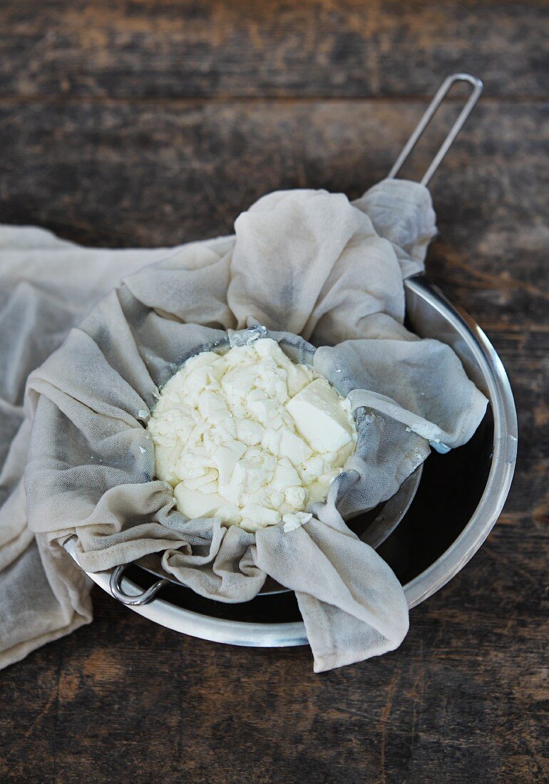 Homemade stacchino (Italian cream cheese) in a sieve