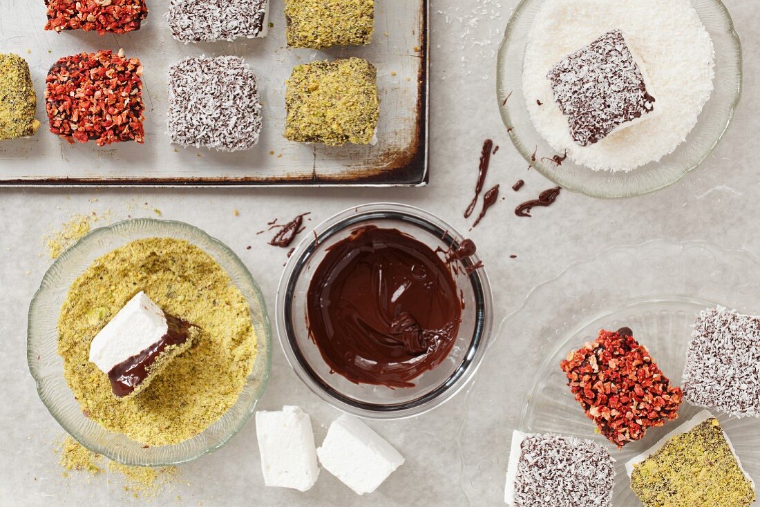 Marshmallows being dipped in chocolate and toppings