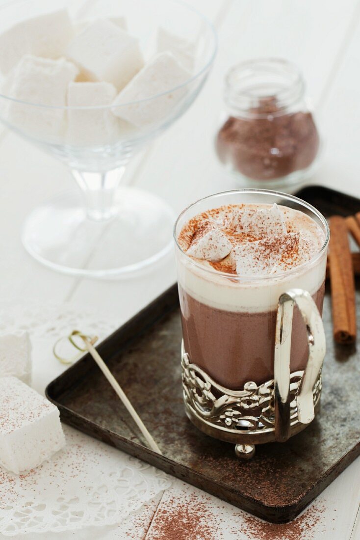 A glass cup of hot chocolate with whipped cream and homemade marshmallow cubes
