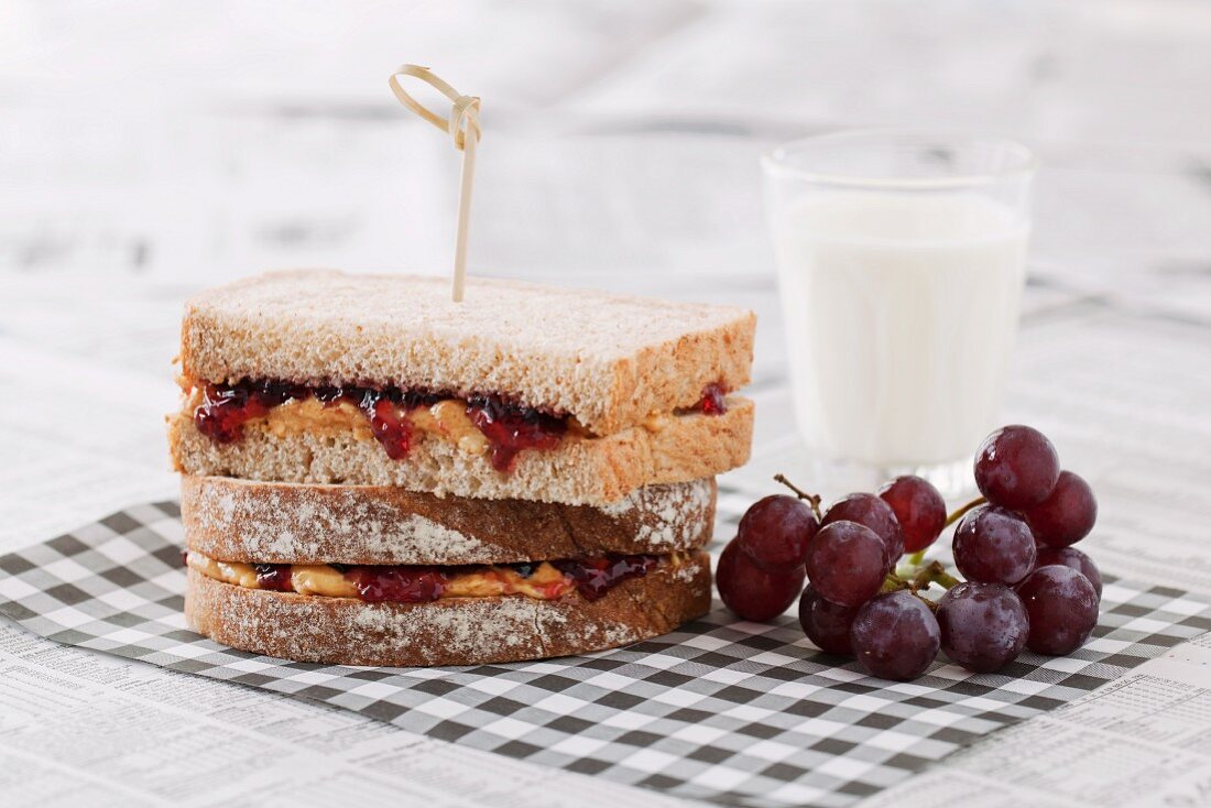 Peanut butter and jam sandwiches served with red grapes and a glass of milk (USA)
