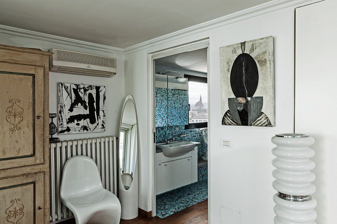 White, classic plastic chair next to open door with view into bathroom