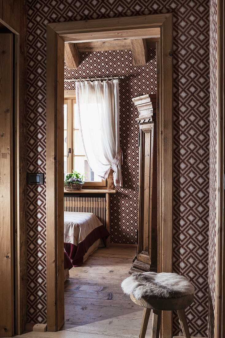 View from hallway into guest room with brown and white textile wallpaper in geometric pattern