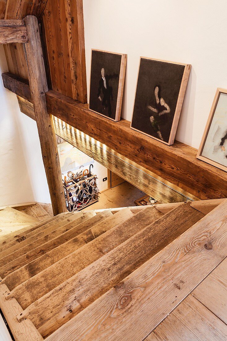 Rustikaler Treppenabgang und seitlich an der Wand aufgestellte Sammlung moderner, chinesischer Kunstbilder (Zeng Fanzhi)