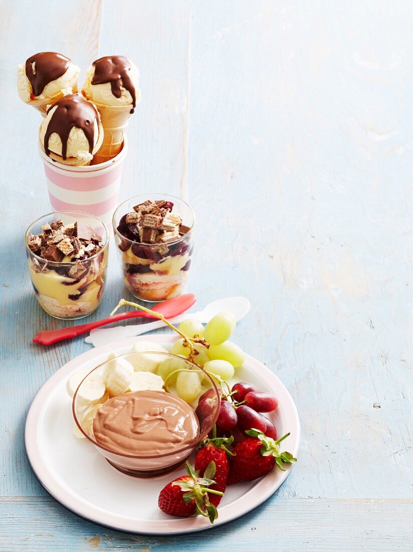 Verschiedene Desserts: Früchte mit Schokoladendip, Eistüten mit Schokoglasur, Trifle