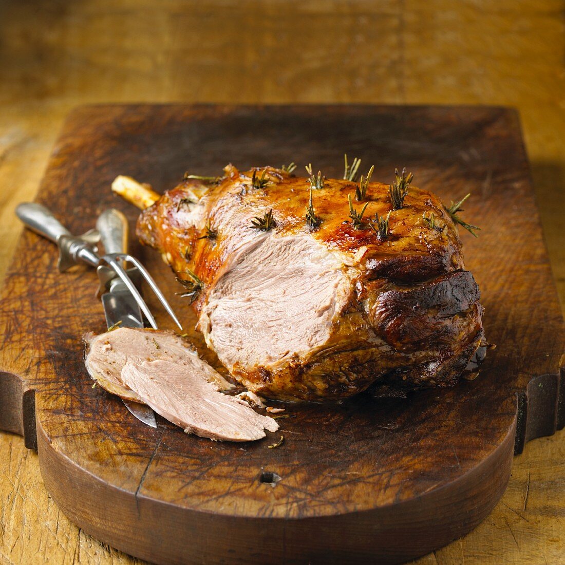 Leg of Lamb on a Cutting Board; Partially Sliced; Decanter of Wine