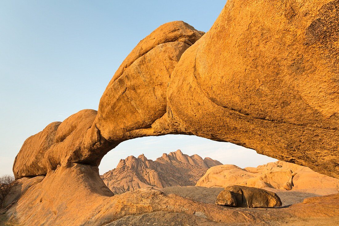 Natürliche Felsbrücke 'Rock Arch' im Spitzkoppe-Gebiet mit Blick auf die Pondok-Berge, Erongo-Gebirge, Namibia