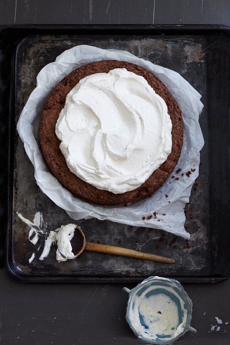 Nusskuchen zubereiten: Kuchen mit Sahnecreme bestreichen