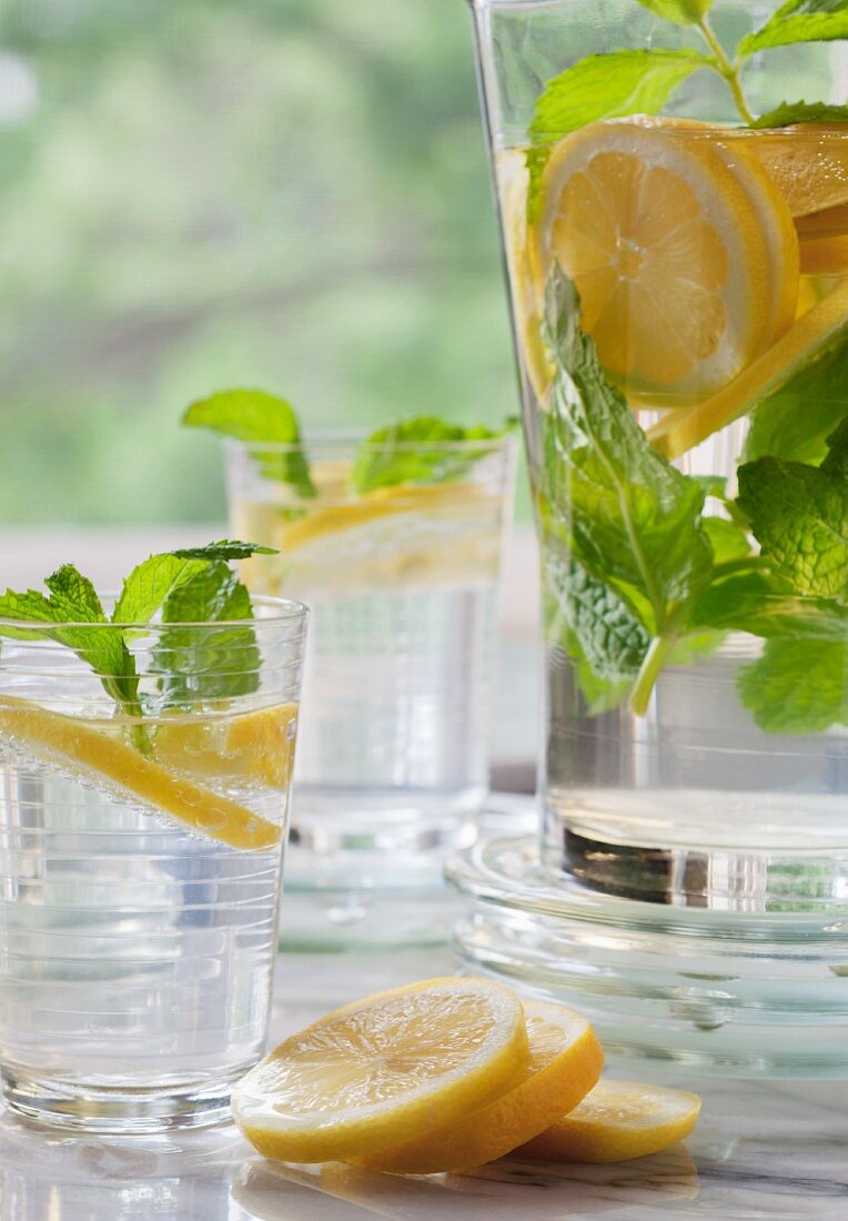 Lemon water with mint in two glasses and a jug