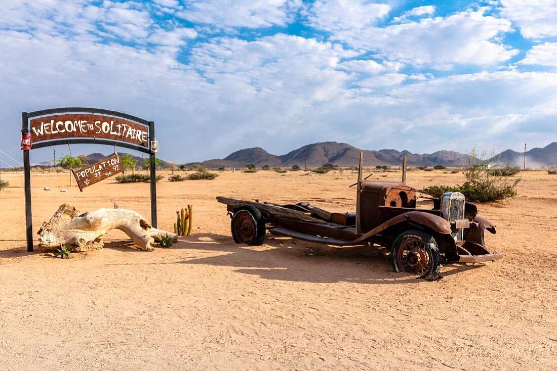 A welcoming wrecked car next to a place name sign, Solitaire, Namibia