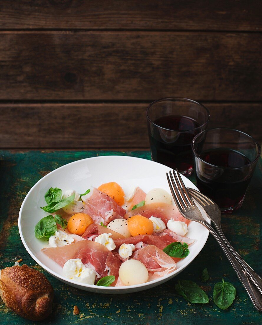 Melon with Prosciutto and mozzarella served with red wine and baguette