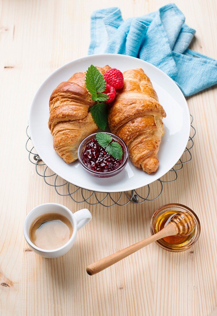 Croissants mit Himbeermarmelade, Honig und Kaffee