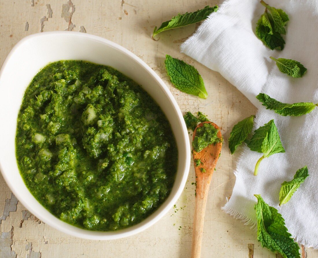 A bowl of mint chutney and fresh mint