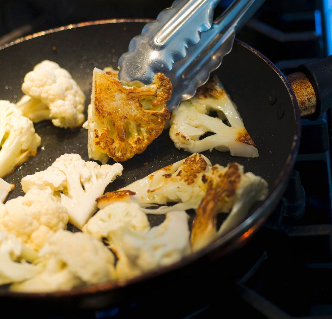 Cauliflower being fried in a pan