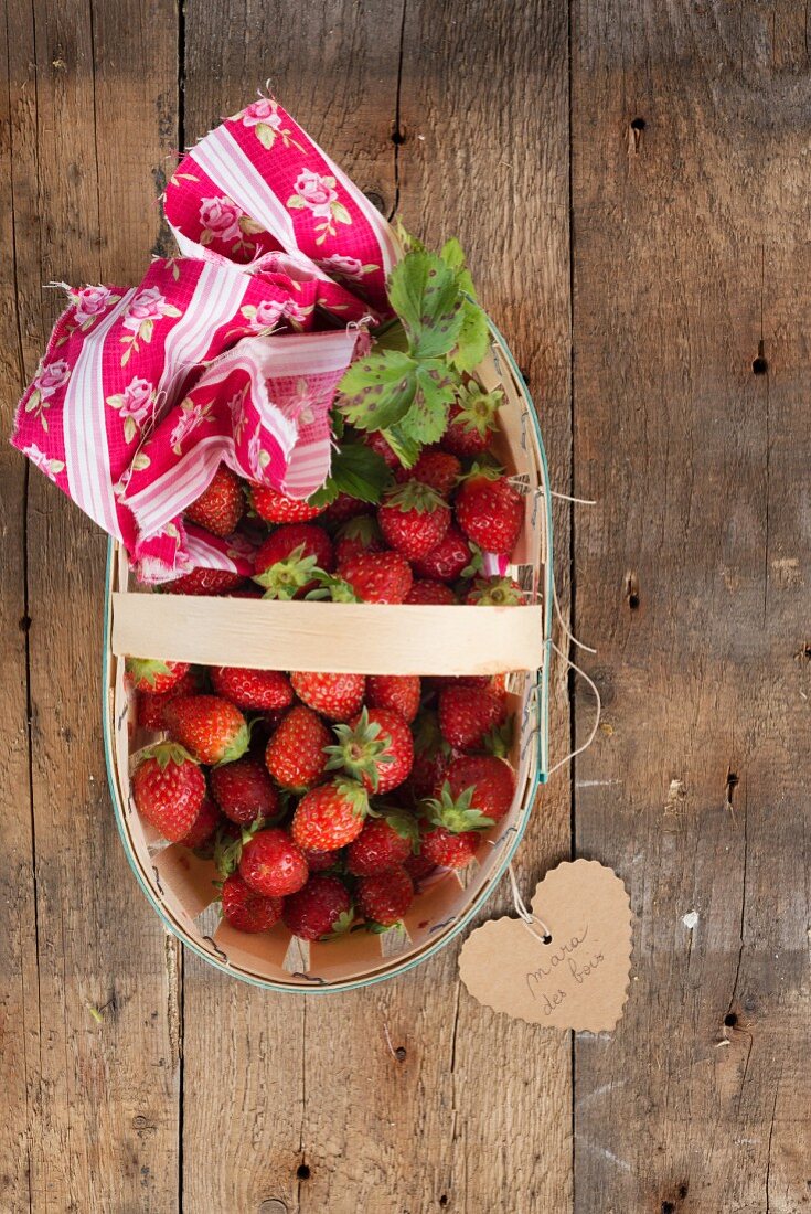 Strawberries in a wooden basket with a heart-shaped label