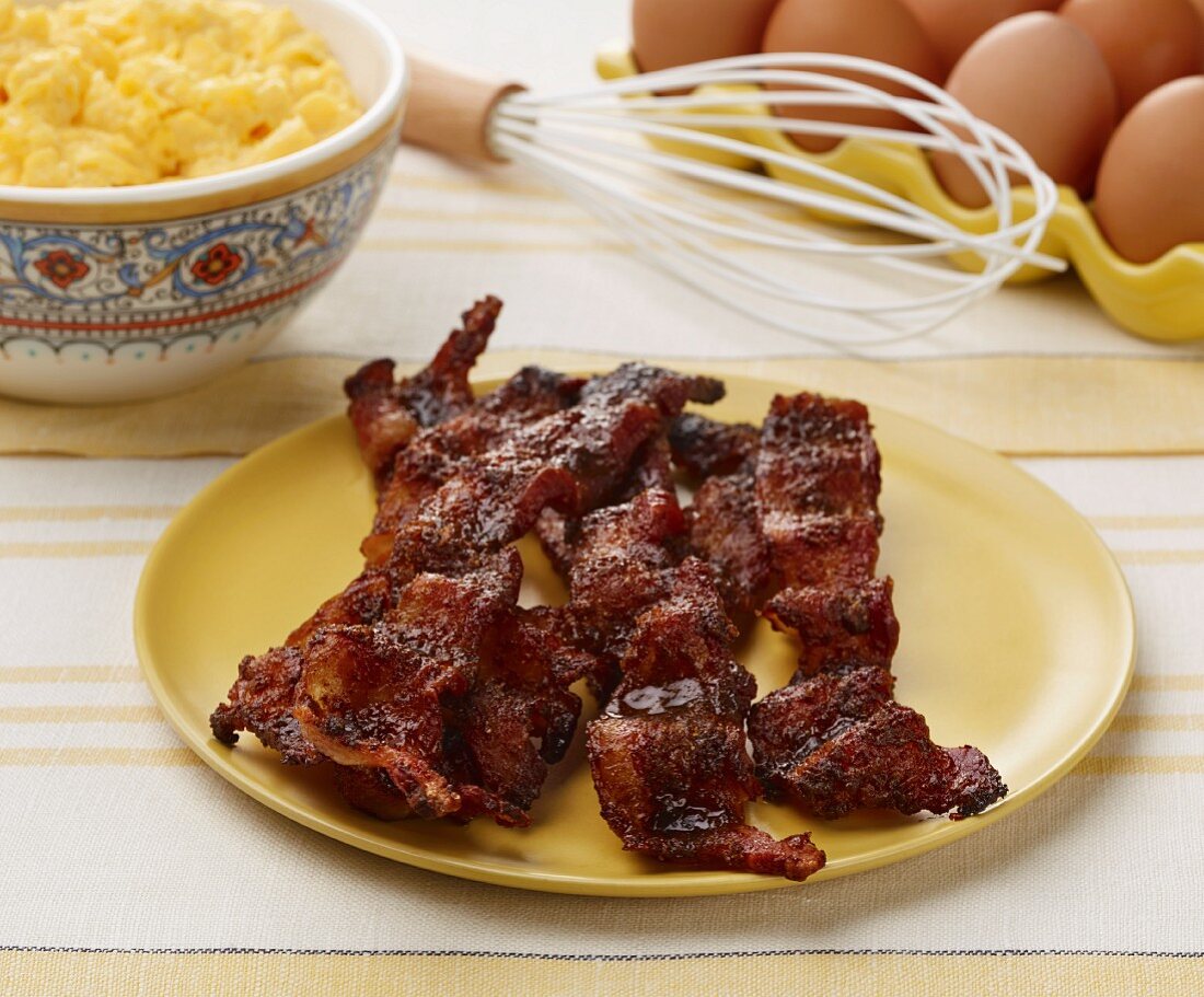 Candied rashers of bacon, scrambled eggs, whisk and eggs