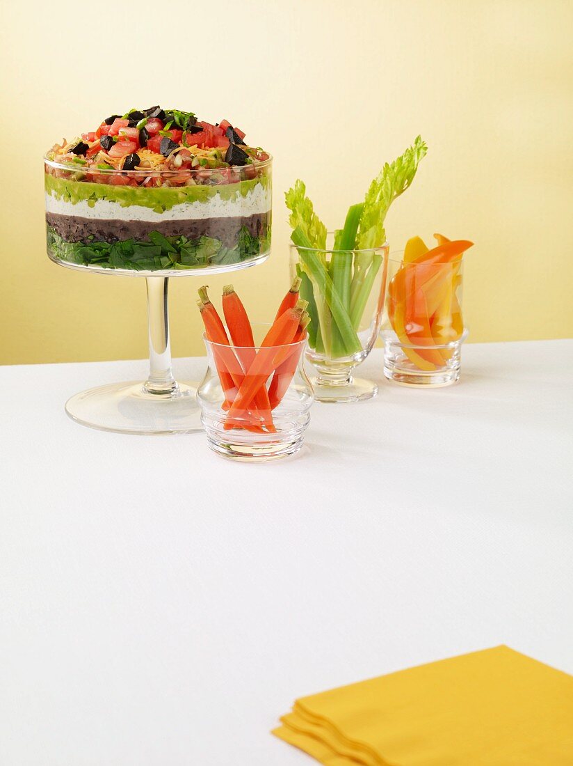 A layered vegetable dip with avocados, olives, tomatoes and yogurt