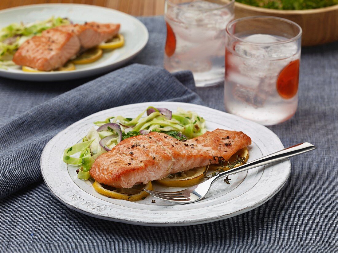 Salmon fillet on a bed of lemons with cucumber salad
