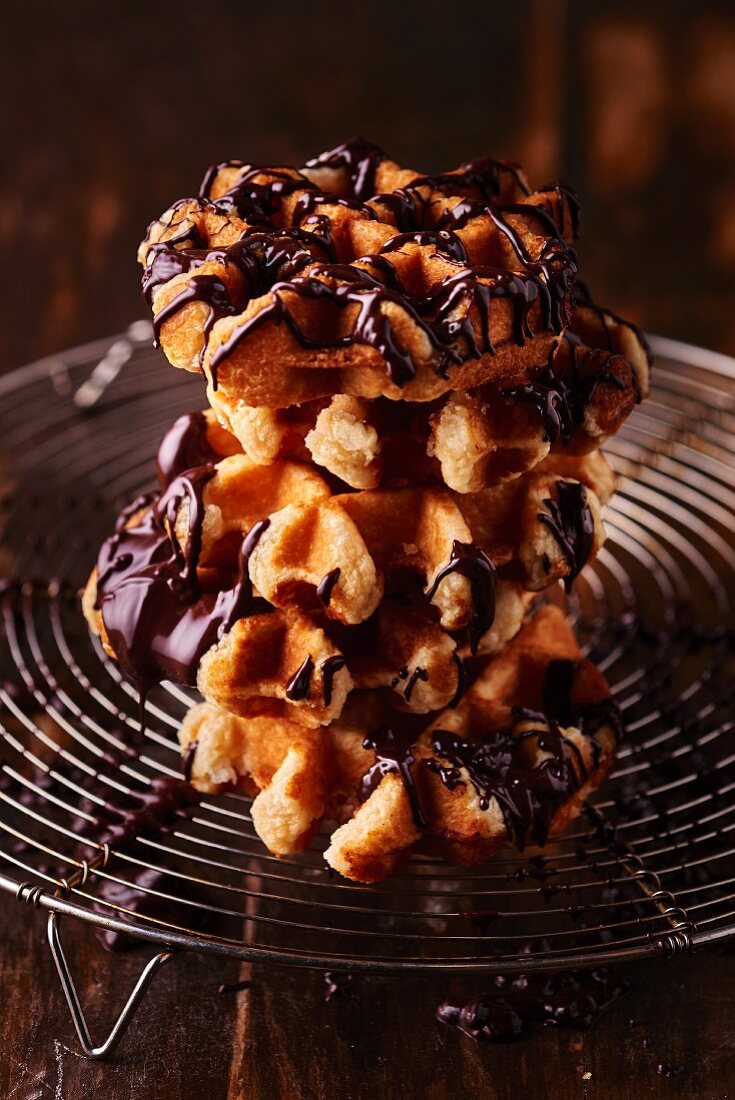 A stack of chocolate-glazed waffles on a wire rack